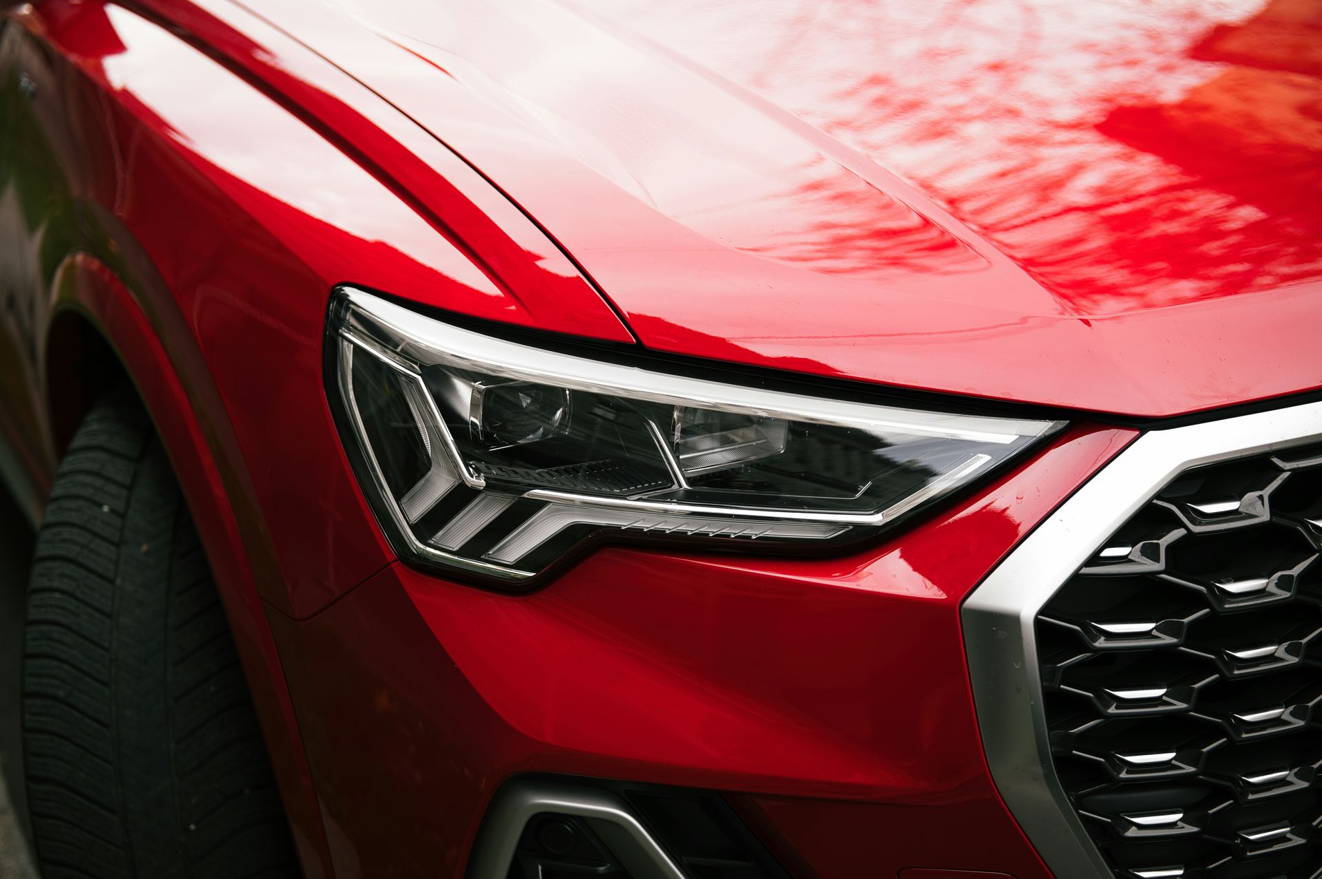 Close-up of a red car's headlight and grille
